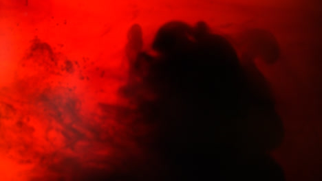 Red-And-Black-Paint-Or-Dye-Dropped-Into-Water-Against-White-Background-To-Create-Swirling-Colourful-Smoke-Background-2